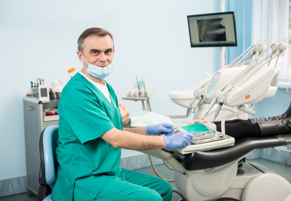 Handsome male dentist with dental tools in the dental office dentist owner